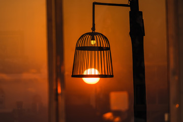 Silhouette Bird cage decorated as outdoor light post with the evening sun in sunset time.Thailand.
