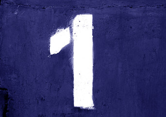 Number 1 in stencil on metal wall in blue color.