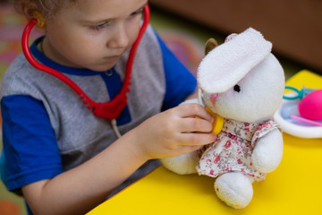 Little boy plays doctor, treats a teddy bunny