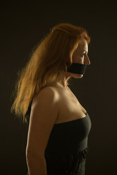 Calm woman with bare shoulders and black band on her mouth