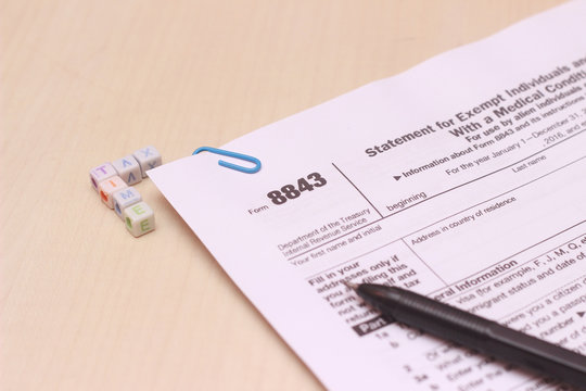 close up of USA tax form type 8843, statement for exempt individuals and individuals with a medical condition and black pen