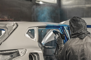 Employee car body painting shop carries out painting of the internal elements of the car