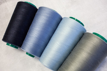 Four spools of cold colors: gray, blue and light blue. Sewing production and home crafts