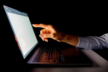 Obraz na płótnie Canvas female hands on the laptop keyboard on a dark background