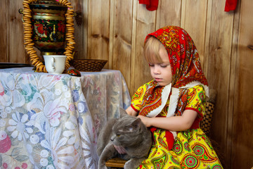 A little girl in russian folk clothes at the celebration of the slavic holiday of Maslenitsa plays...