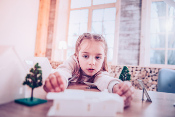 Concentrated schoolgirl congregating toy constructor at cozy home
