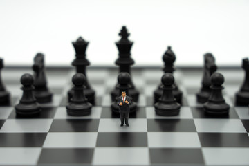 Miniature people businessmen standing on a chessboard with a chess piece on the back Negotiating in business. as background business concept and strategy concept with copy space.