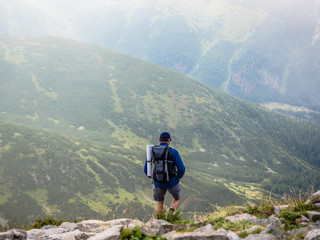 Fototapeta na wymiar A man back with backpack for camping is trekking on a mountain having fun, walking along the distance on his holiday at Tatra mountain, Poland, Slovakia.
