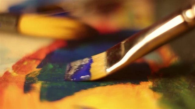 The artist puts strokes of blue paint on canvas.Macro shooting.