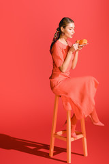 fashionable woman holding plate with macaroons on living coral.  color of the year 2019 concept