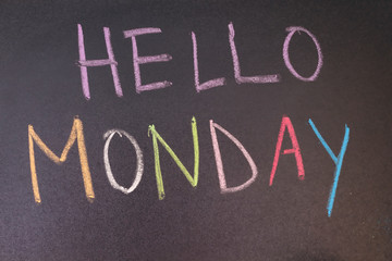 handwriting hello monday on chalkboard with colorful chalk and wooden heart