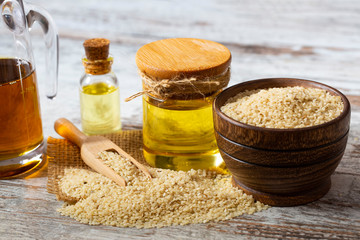 Sesame seeds in sack and bottle of oil on wooden rustic table