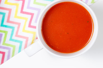 Bowl of tomato soup isolated on white background with shadows, top view