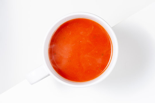 Bowl of tomato soup isolated on white background with shadows, top view
