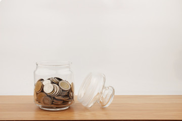 Coin in glass on wooden table for investment and interest concept