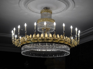 Old vintage chandelier with light candles in a palace ceiling, living room.
