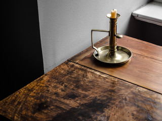Vintage retro old lighted candle and candlestick on a wooden texture table with text copy space.