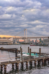 Rainbow Bridge with Cargo and cruise ships moored or sailing in the Odaiba Bay of Tokyo.