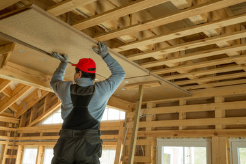 Fototapeta premium Construction worker thermally insulating eco wooden frame house