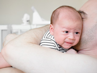 Young father holding crying sleepy cute little newborn baby in his arms with care,  Little mixed race Asian and Caucasian baby, Thai-Polish