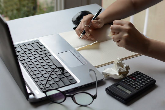 Woman's hands at the office desk are splitting paper in front of the laptop. The accountant makes a mistake in the account. A nervous girl who works from home clears her notes. Student teaches for exa