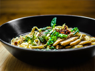 Thai Chinese style hot stewed Duck noodles soup served in a black bowl, egg noodles and chili oil on top.
