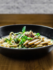 Thai Chinese style hot stewed Duck noodles soup served in a black bowl, egg noodles and chili oil on top.