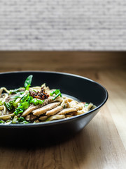 Thai Chinese style hot stewed Duck noodles soup served in a black bowl, egg noodles and chili oil on top.