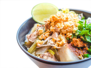 Shred chicken instant noodles with deep fried garlic. chili powder, lemon, spring onion and hot soup with spices in a bowl on white table, Thai noodles food