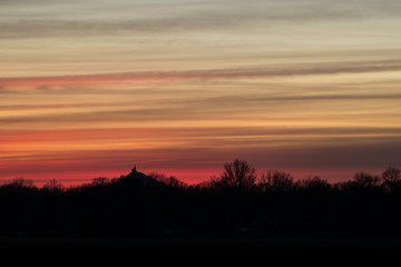 Countryside during sunset, silhouette of trees and castle on a hill with very colorful skies in the background. Amazing spring scene.