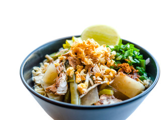 Shred chicken instant noodles with deep fried garlic. chili powder, lemon, spring onion and hot soup with spices in a bowl on white table, Thai noodles food.