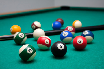 Many billard balls and a cue in a leisure club environment, lots of billiards on the table, wallpaper background