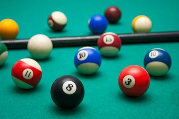 Foto op Plexiglas Lots of billiards and the cue on the billiard table, sports and recreation. Focus on the eight ball © Tomasz
