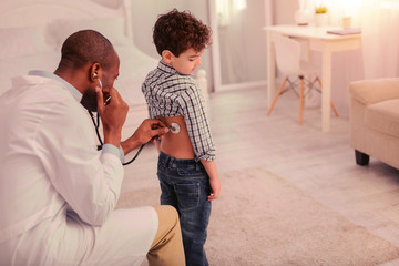 Doctor meticulously examining child having breathing problems