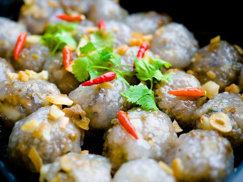 Thai appetizer, Steamed tapioca balls with peanut and pork filling with chilis, coriander and garlic in a black plastic food tray box for take away home.