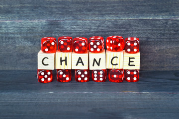 Word Chance written on wooden cubes and red dice on the dark background.