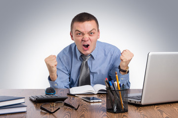 Angry businessman shouting in office on gray background
