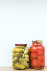 Marinated cucumbers and tomatoes in jars. Space for text.