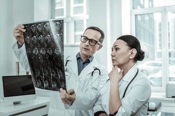 Couple of medical specialists incomprehensibly looking on the knee bone