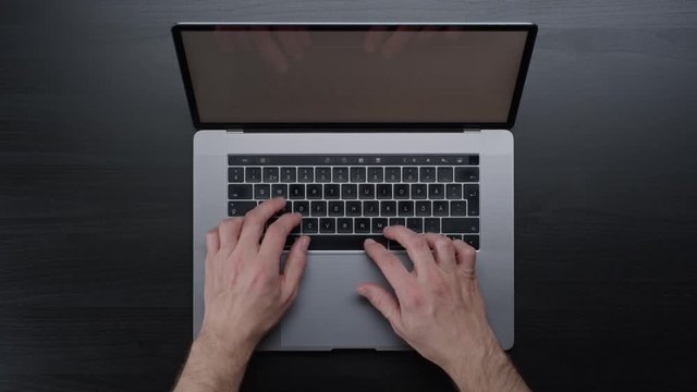 Male hands typing laptop on black clean minimalistic table with top view, gestures and finger movements