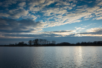 Highlighted clouds through the sun over a lake