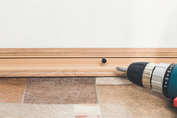 Installation of plastic floor plinth. Interior details.