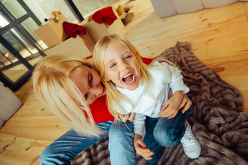 Cheerful blonde girl laughing while being tickled