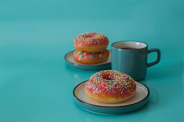 Pink glazed doughnuts with sprinkles on turquoise background