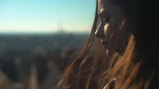 Lonely pensive young lady standing on skydeck, upset wit personal troubles