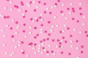 Small white and pink candy hearts, closeup on a pink background for wallpaper, card, invitation or poster