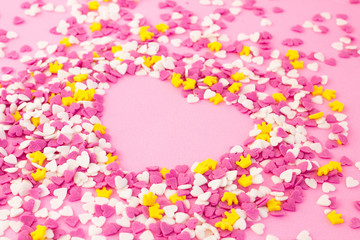 Confectionery decorations around a pink heart, sugar sprinkle sweets background for wallpaper,...