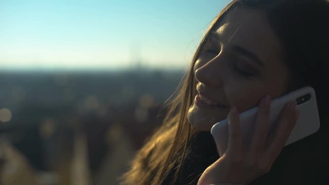 Beautiful young female chatting on phone on skydeck sharing impressions, roaming