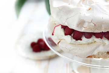 Tort bezowy z bitą śmietana i malinami. © foodandcook