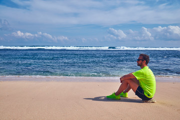 Sportsman stretching on a exotic tropical beach after jogging / exercising.